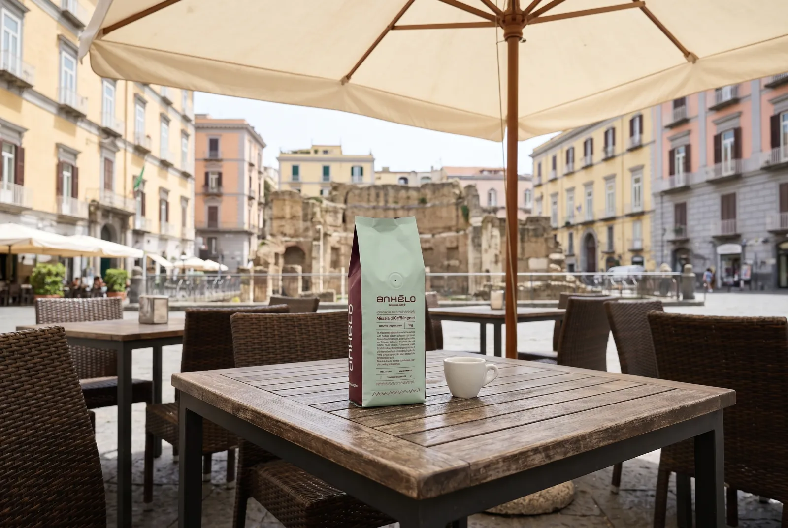 Anhelo whole beans pack and cup on a wooden table at an outdoor café in a square in Naples