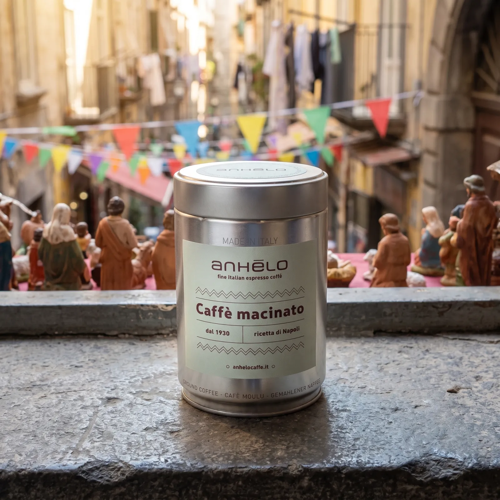 Anhelo ground coffee tin on a stone windowsill, with a Naples lane and nativity-scene figurines in the background